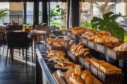 Mesa de buffet repleta de pães e doces variados em um salão de jantar de restaurante bem iluminado.