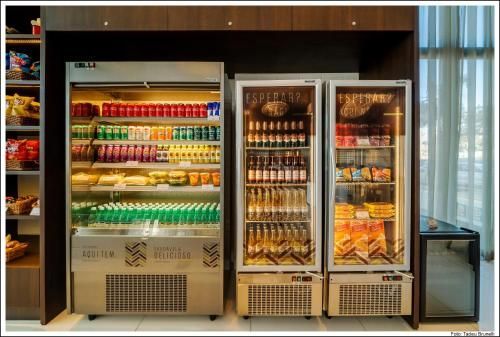 Vitrines refrigeradas bem abastecidas com bebidas e lanches coloridos em uma loja moderna.