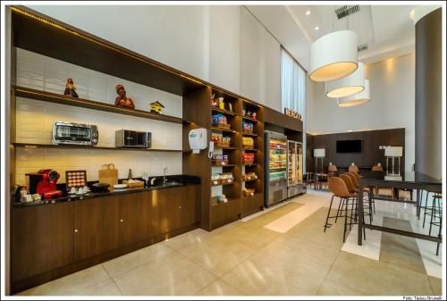 Interior de café moderno com prateleiras de madeira, balcão de café e área de estar sob luminárias pendentes.