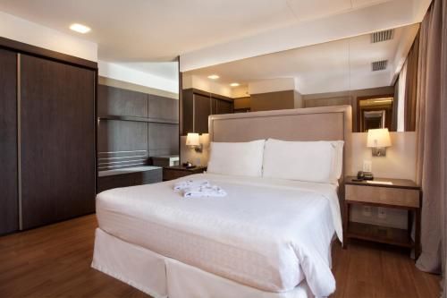 Quarto de hotel moderno com cama king-size, piso de madeira e iluminação aconchegante.