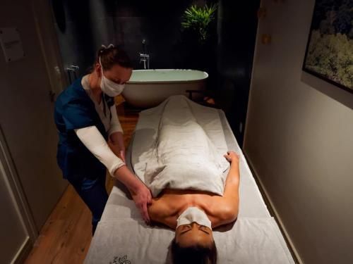 Massagista trabalhando nas costas de um cliente em uma sala de spa com pouca luz.