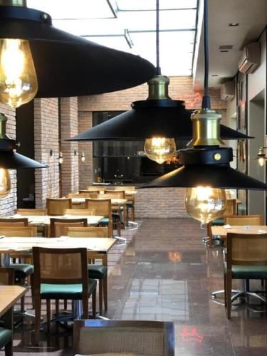 Interior de restaurante moderno com luminárias pendentes, mesas de madeira e paredes de tijolos.