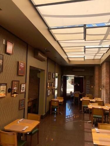 Pátio interno do restaurante com mesas, cadeiras e teto com claraboia.