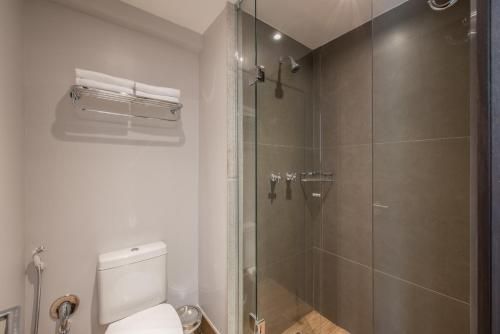 Banheiro pequeno e moderno com vaso sanitário, box de vidro e paredes revestidas com azulejos bege.
