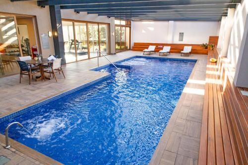 Piscina coberta com água azul, espreguiçadeiras e deck coberto.