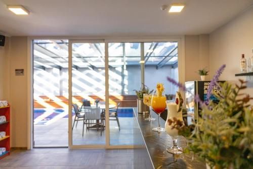 Interior de café moderno e luminoso com portas de vidro, mesas e um balcão com flores e bebidas de frutas.