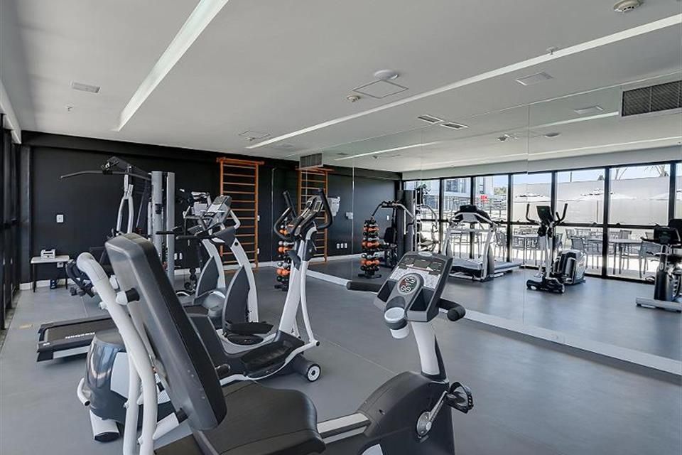 Academia moderna com aparelhos de cardio, equipamentos de musculação e paredes espelhadas em um ambiente amplo e iluminado.