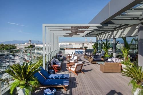 Terraço na cobertura com espreguiçadeiras, palmeiras em vasos e vista para a cidade sob uma pérgola moderna.