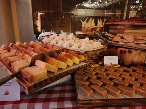 Buffet de sobremesas com uma variedade de doces, bolos e chocolates em bandejas sobre uma toalha de mesa xadrez vermelha e branca.