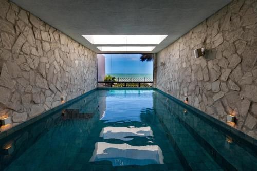 Piscina coberta com paredes de pedra, água azul e vista para o oceano além da abertura.