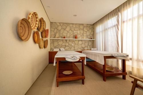 Sala de tratamento de spa com mesas de massagem, decoração de parede em tecido e cortinas transparentes.