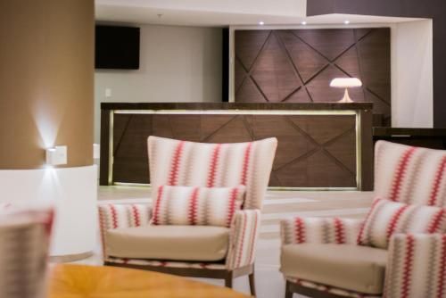 Sala de estar moderna com poltronas listradas, balcão de madeira e decoração geométrica na parede.
