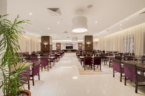 Interior de restaurante moderno e luminoso com cadeiras roxas, piso branco e iluminação suave no teto.