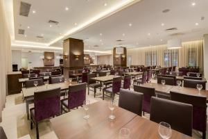 Sala de jantar elegante de restaurante com cadeiras roxas, mesas de madeira e iluminação aconchegante no teto.