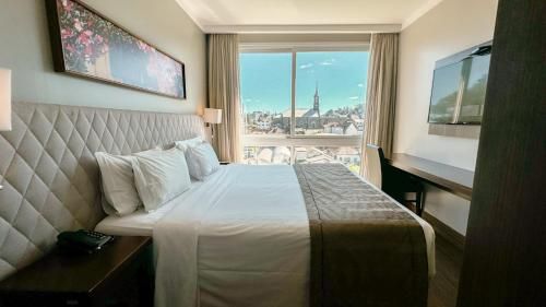 Quarto de hotel luminoso com uma cama grande e vista para o horizonte da cidade através da janela.