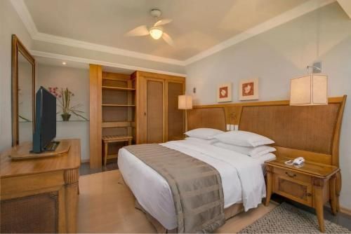 Quarto aconchegante com cama, móveis de madeira, armário aberto e TV sobre a cômoda.