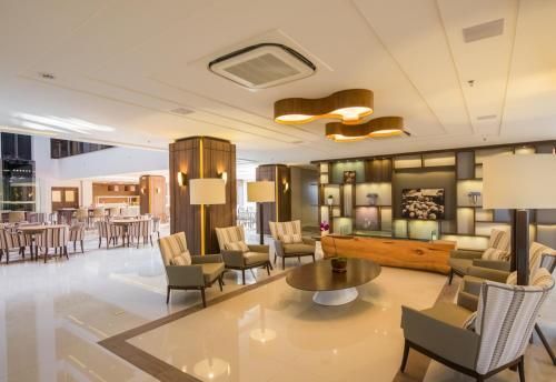 Salão de hotel moderno com cadeiras bege, mesa redonda e iluminação aconchegante.