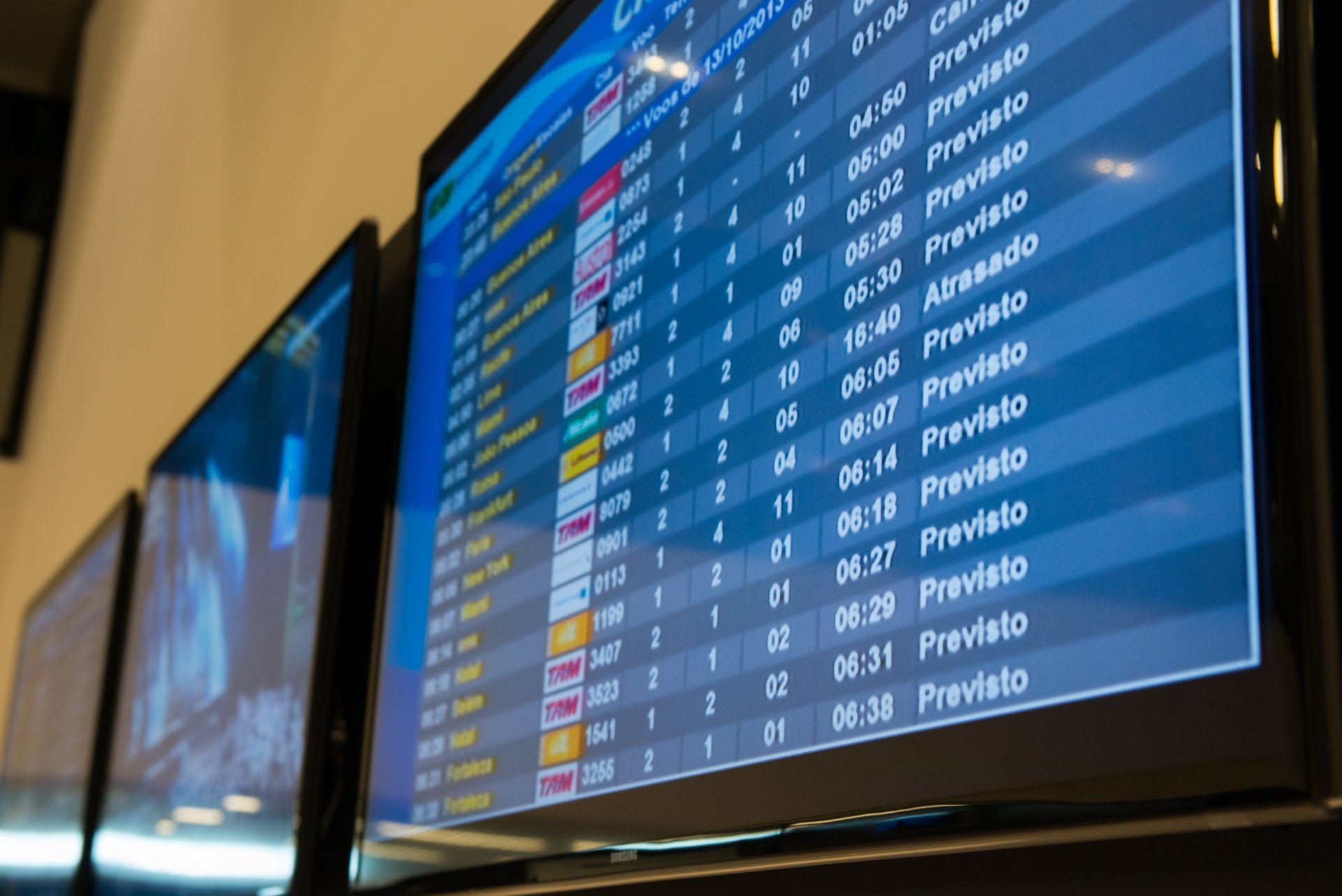 Painéis de partidas de aeroportos exibindo informações de voos em telas azuis e amarelas.