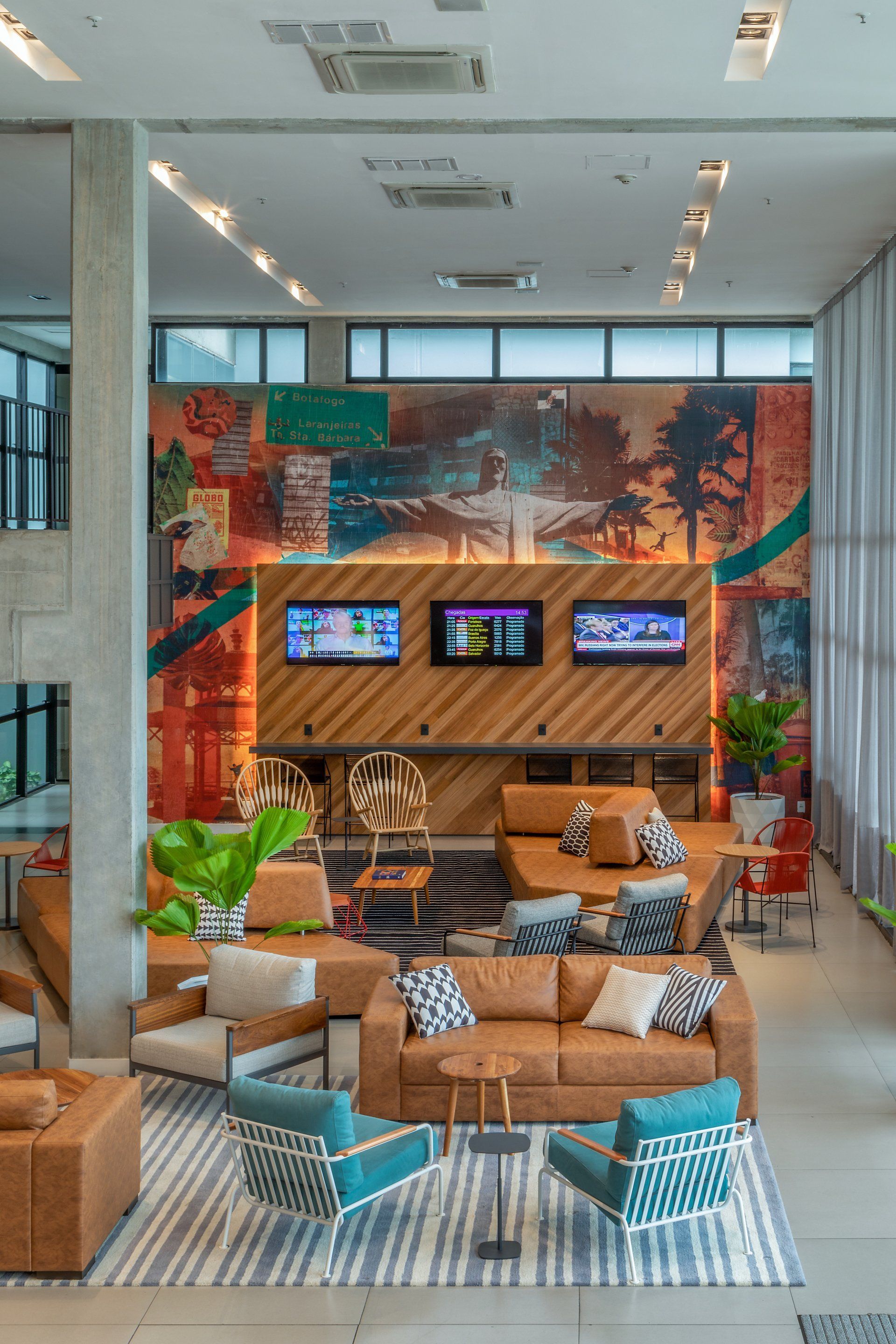 Salão de estar moderno com mural colorido, parede de TV em madeira e assentos em tons de bege e azul.
