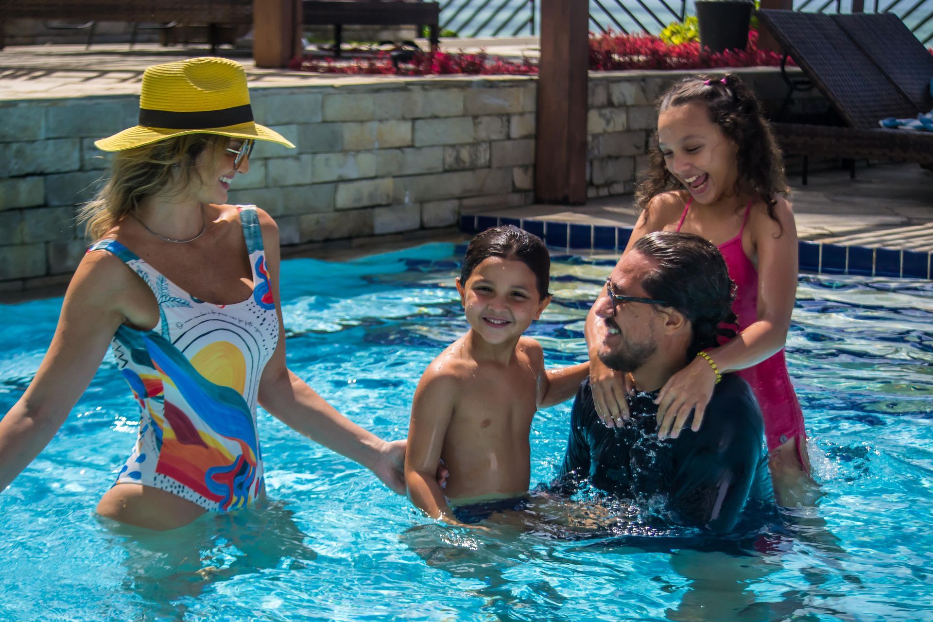 Pessoas brincando em uma piscina, se refrescando e sorrindo em um dia ensolarado.