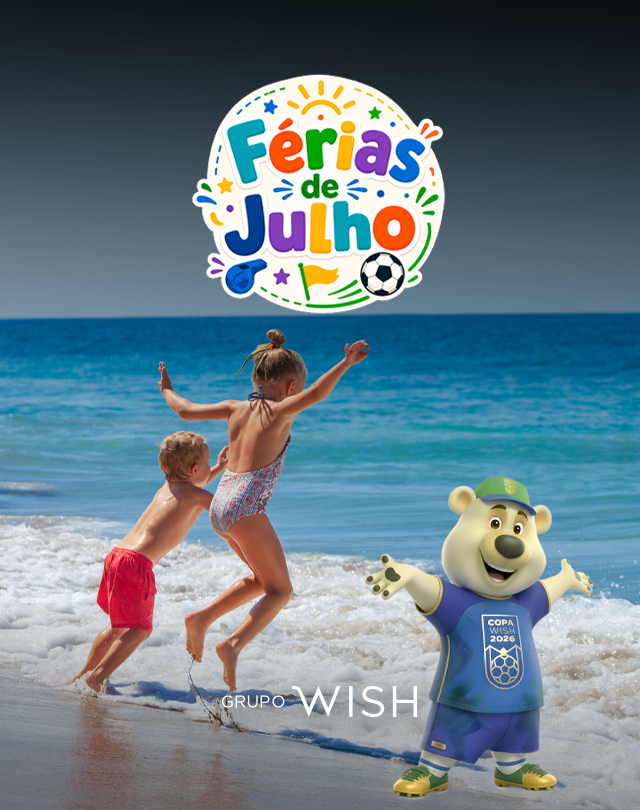 Duas crianças pulam na praia ao lado de um mascote de urso azul, sob o logotipo das “Férias de Julho”.