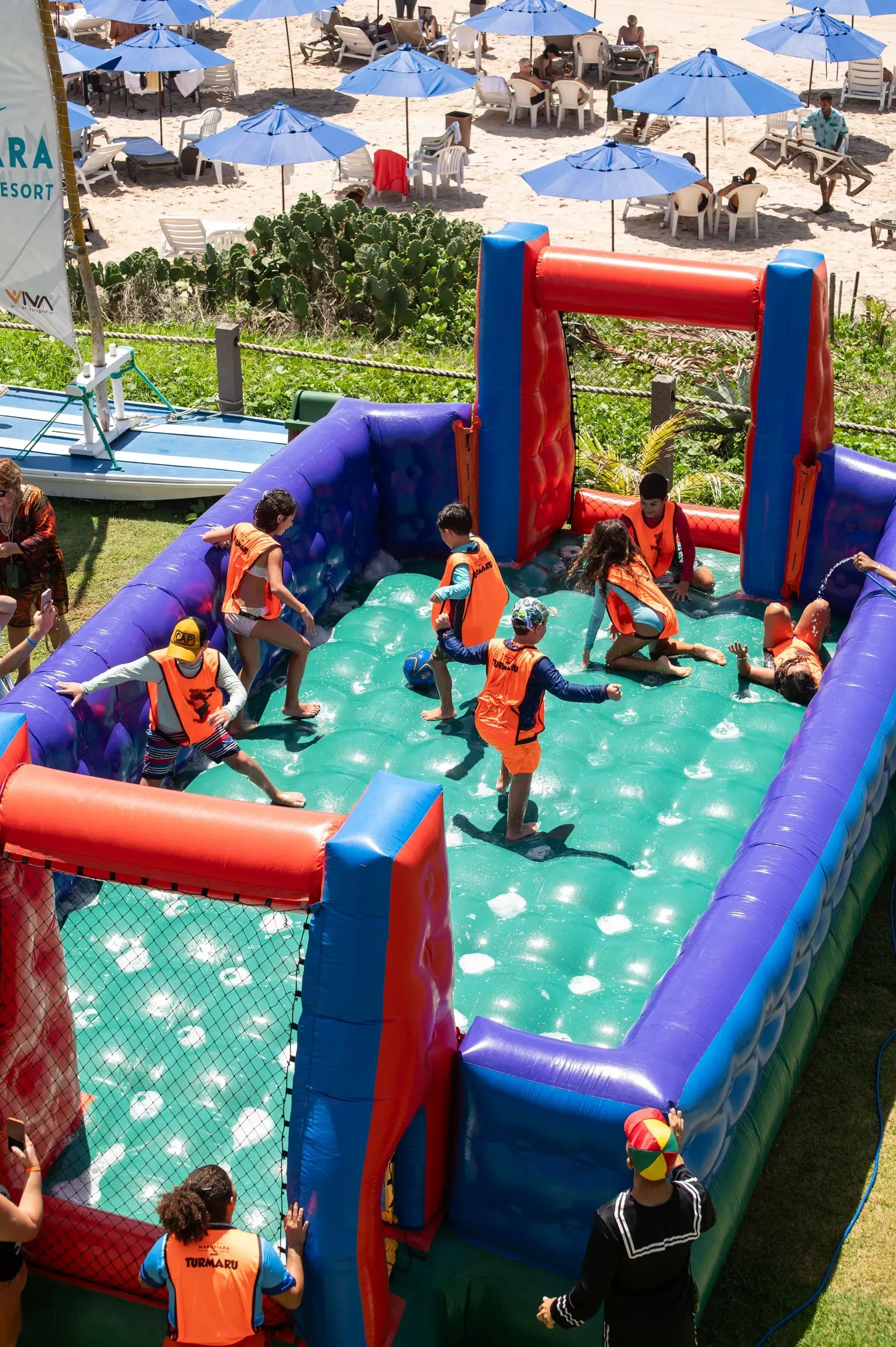 Quatro crianças com fantasias listradas segurando bolos decorados em um cenário de festa colorido.