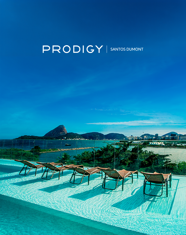 Resort de luxo à beira-mar com piscina, espreguiçadeiras e vista para o oceano sob um céu azul.