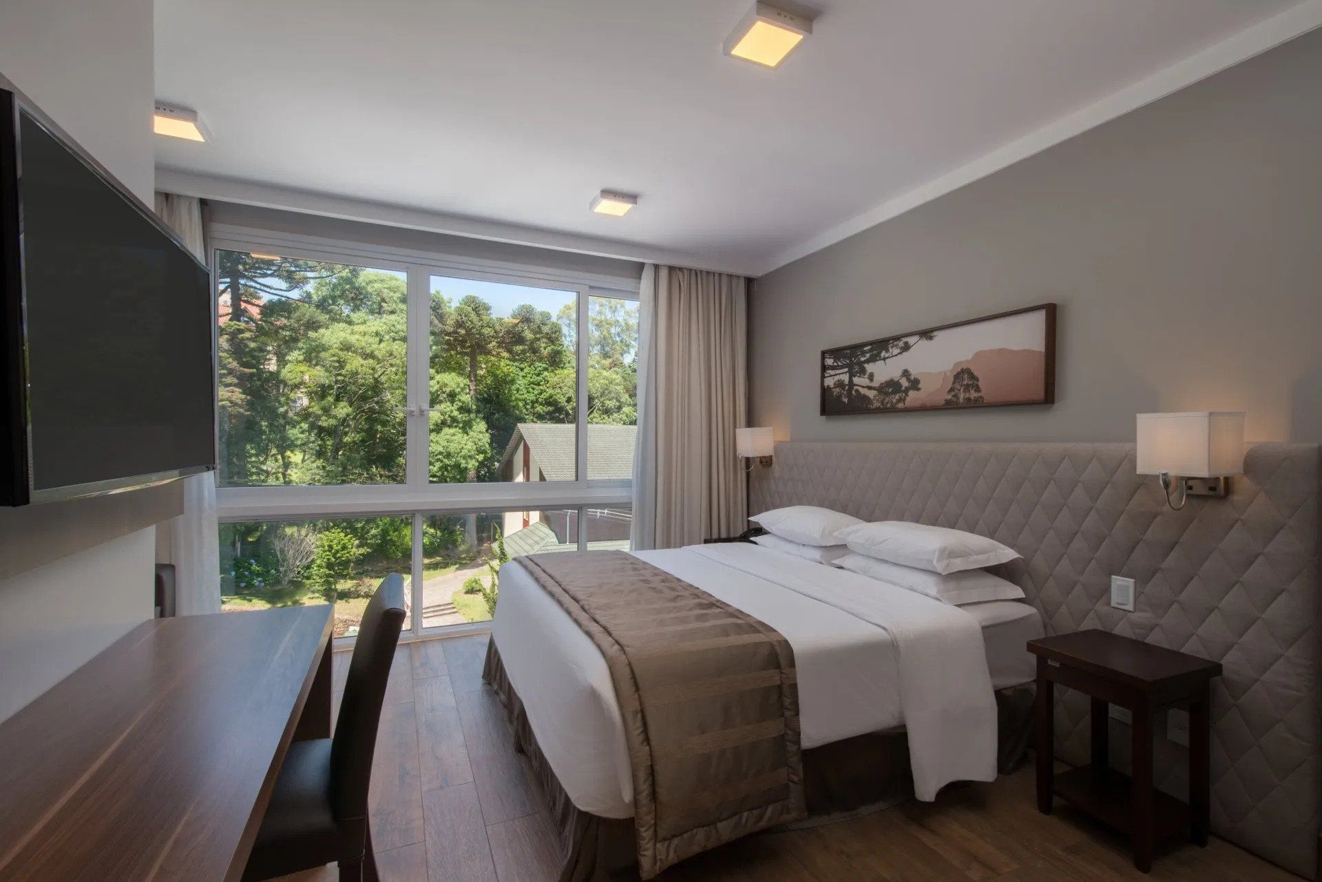 Quarto moderno com janela ampla, duas camas de solteiro, paredes cinza e vista para a floresta.