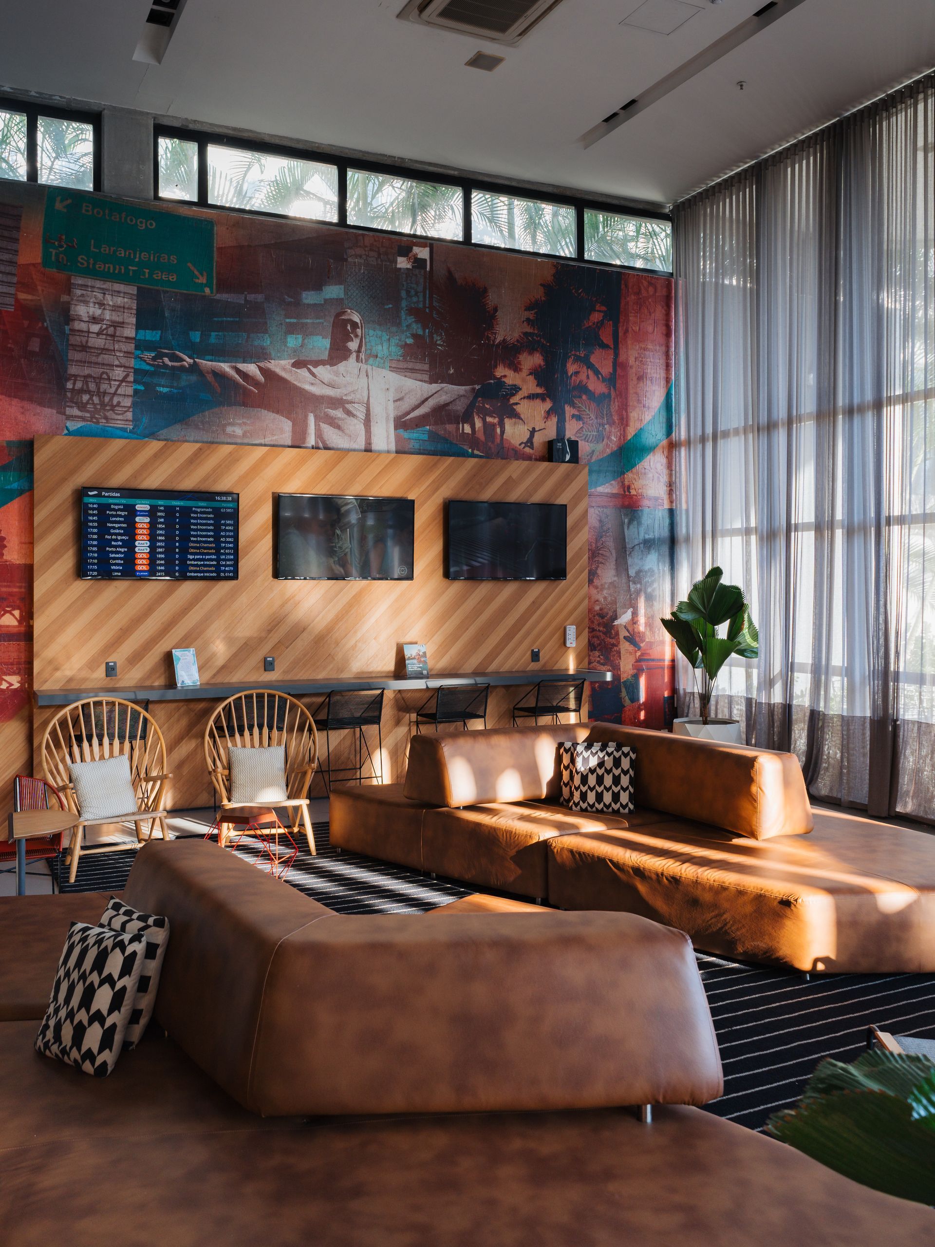 Lobby de hotel moderno com assentos em tons de bege, tapete estampado e parede de destaque em azul.