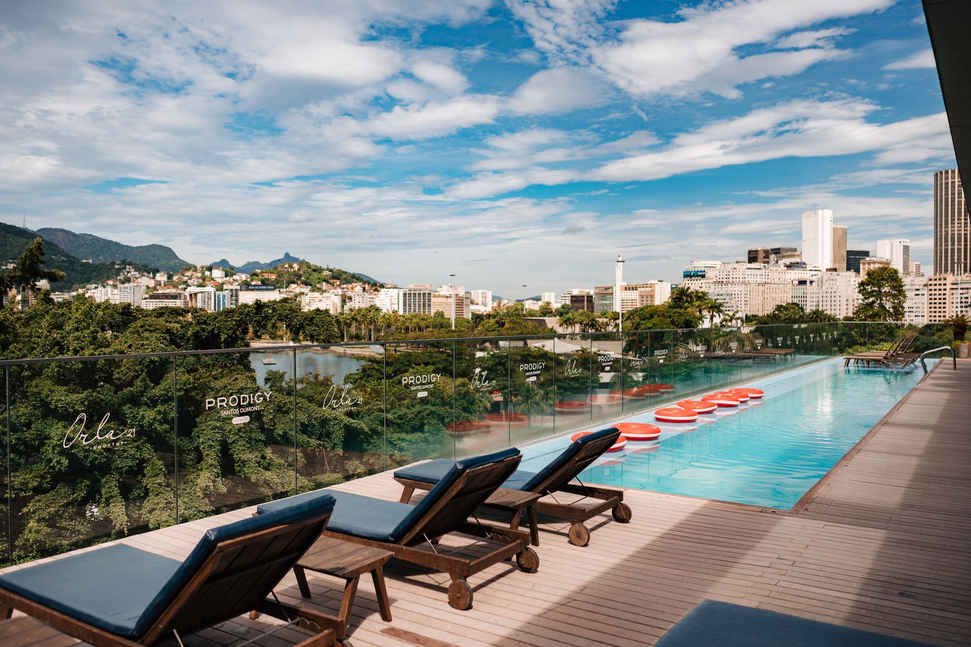 Piscina infinita turquesa com vista para uma baía azul brilhante e montanhas ao longe em um resort de luxo.