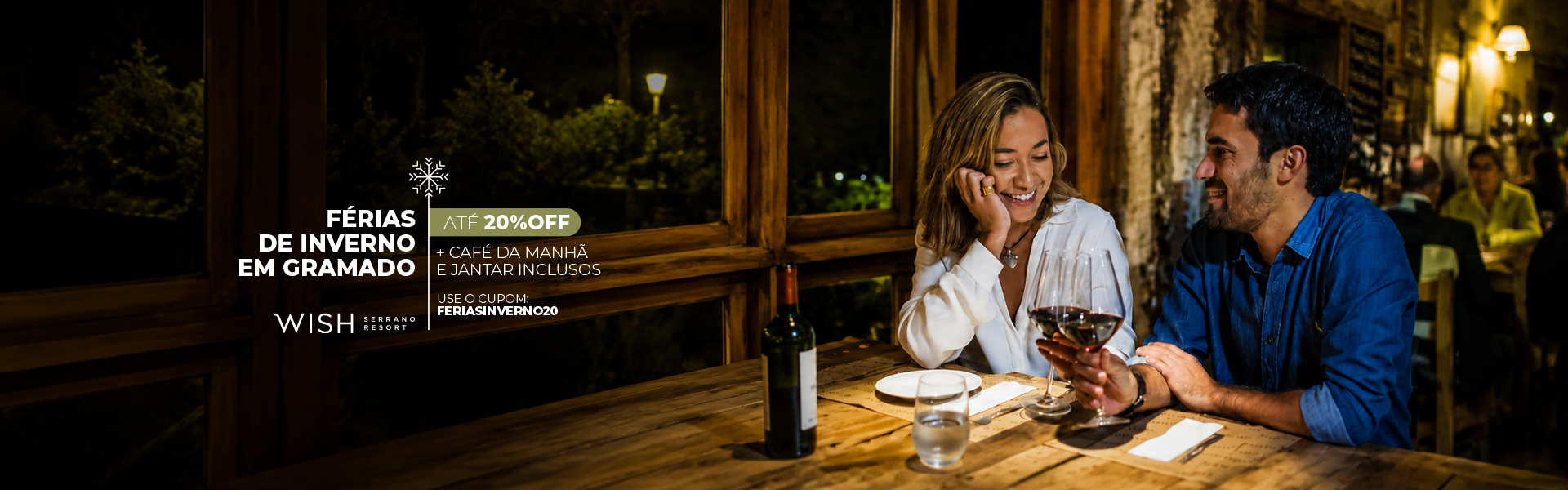 Casal jantando à luz de velas em um restaurante rústico, sorrindo e conversando enquanto bebem vinho.