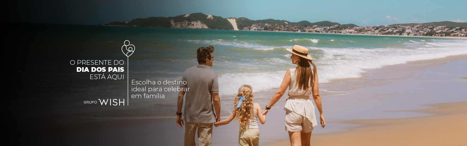 Família caminhando de mãos dadas ao longo de uma praia ensolarada com água turquesa e colinas ao longe.