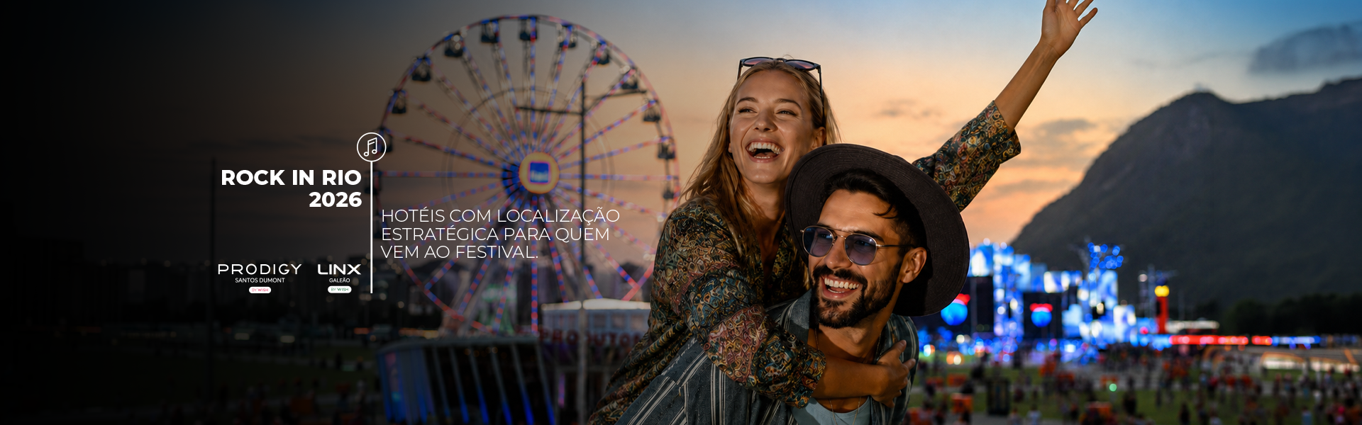 Pessoas sorridentes em um festival na roda-gigante ao pôr do sol, com luzes da cidade e montanhas ao fundo.