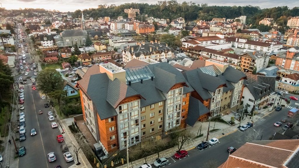 Vista aérea de um quarteirão com prédios de apartamentos coloridos e ruas adjacentes ao entardecer.