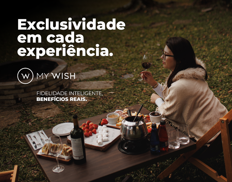 Casal em piquenique ao pôr do sol, com comida e vinho, e texto “Exclusividade em cada experiência”