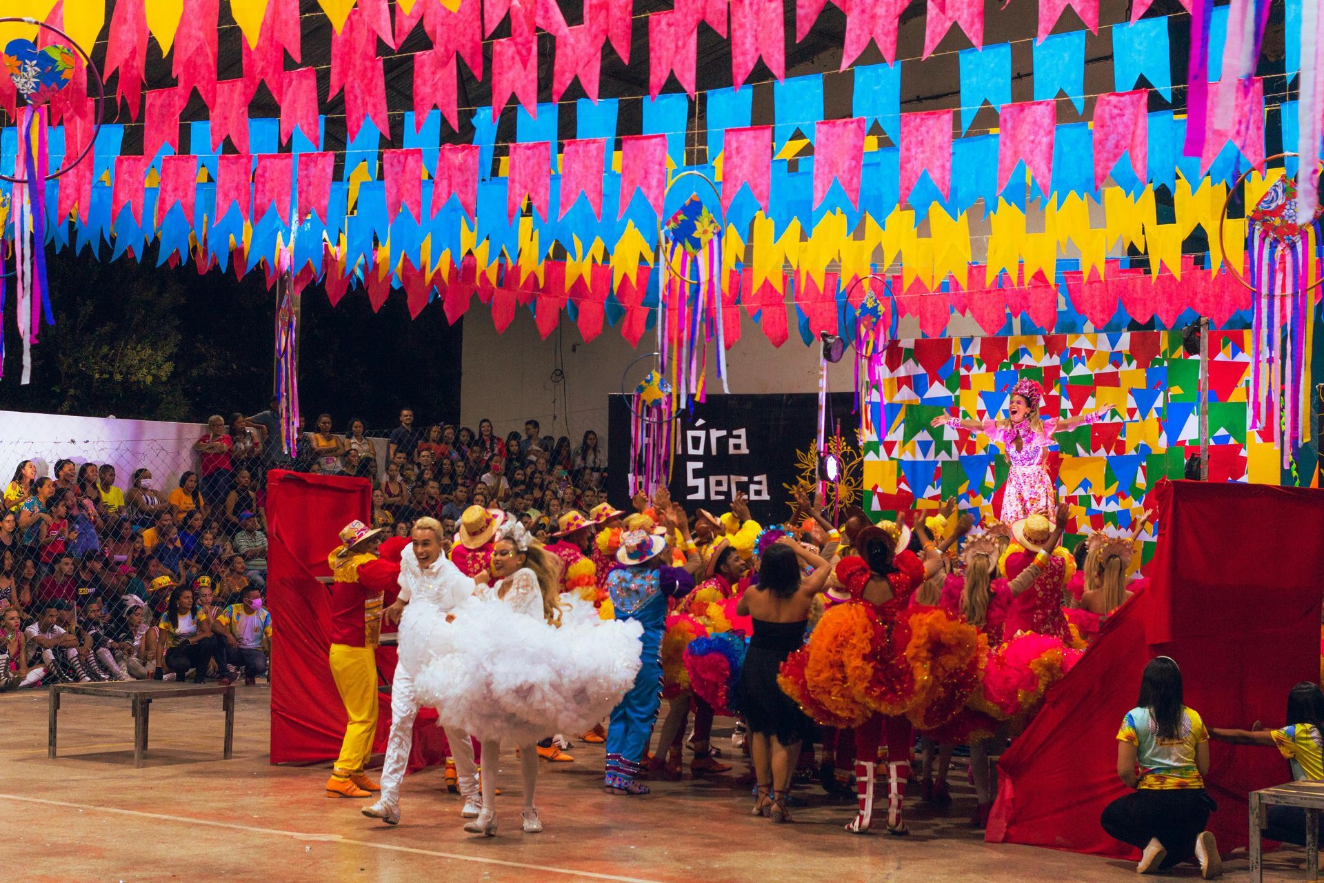 Colorful folk dance performance on a decorated stage with bright flags overhead