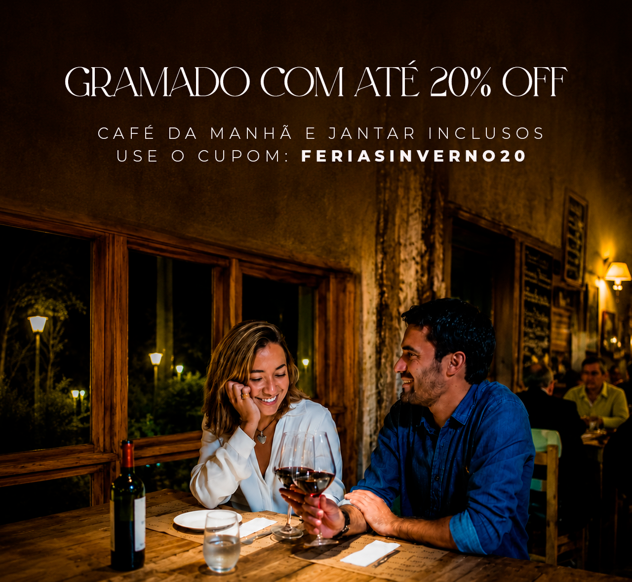 Casal jantando em um restaurante aconchegante, sorrindo enquanto saboreiam vinho e sobremesa, com a mensagem “Gramado.com até 20% de desconto” acima.