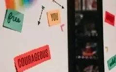 A white board with stickers on it that say free you and courageous.