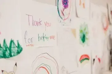 A white board with drawings on it and a note that says `` thank you for helping me ''.