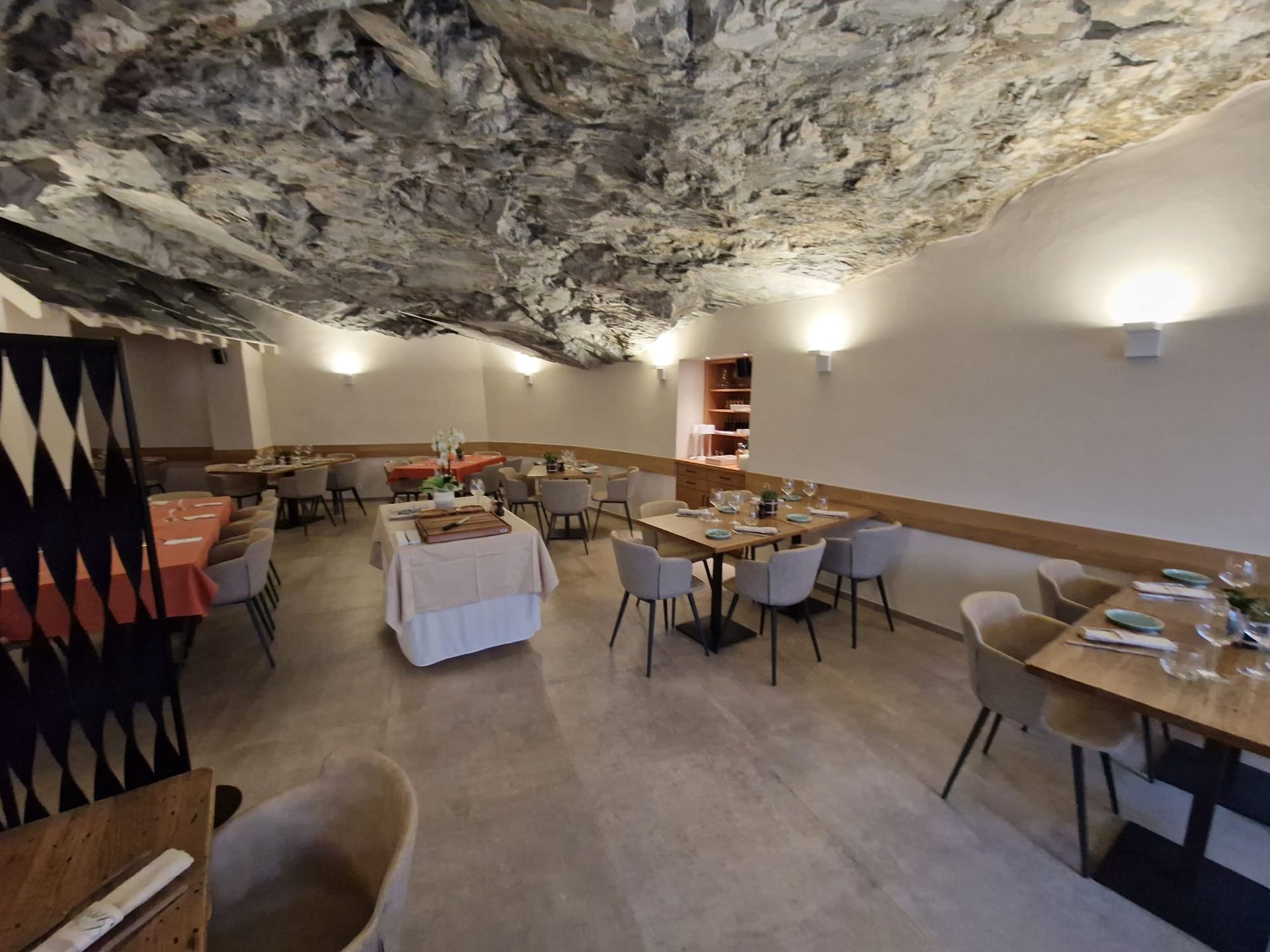 Une grande salle à manger avec tables et chaises et un plafond troglodyte.