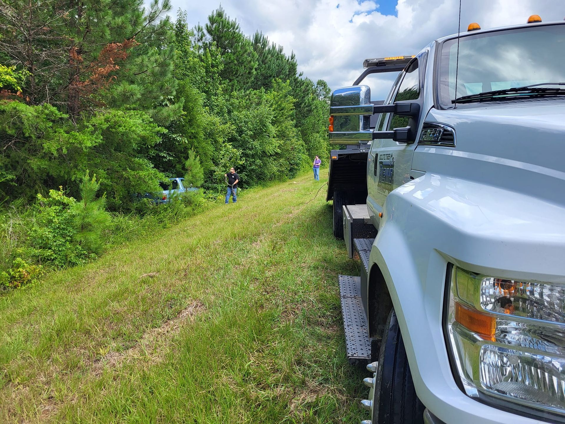 White pickup trucks parked beside a grassy roadside with trees and a cloudy sky