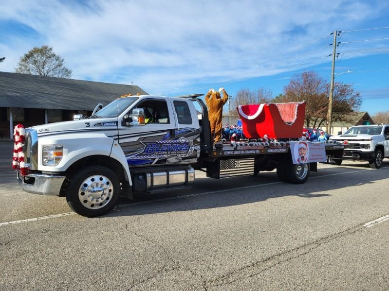 White pickup truck with a holiday parade float and red Santa decoration driving down a street