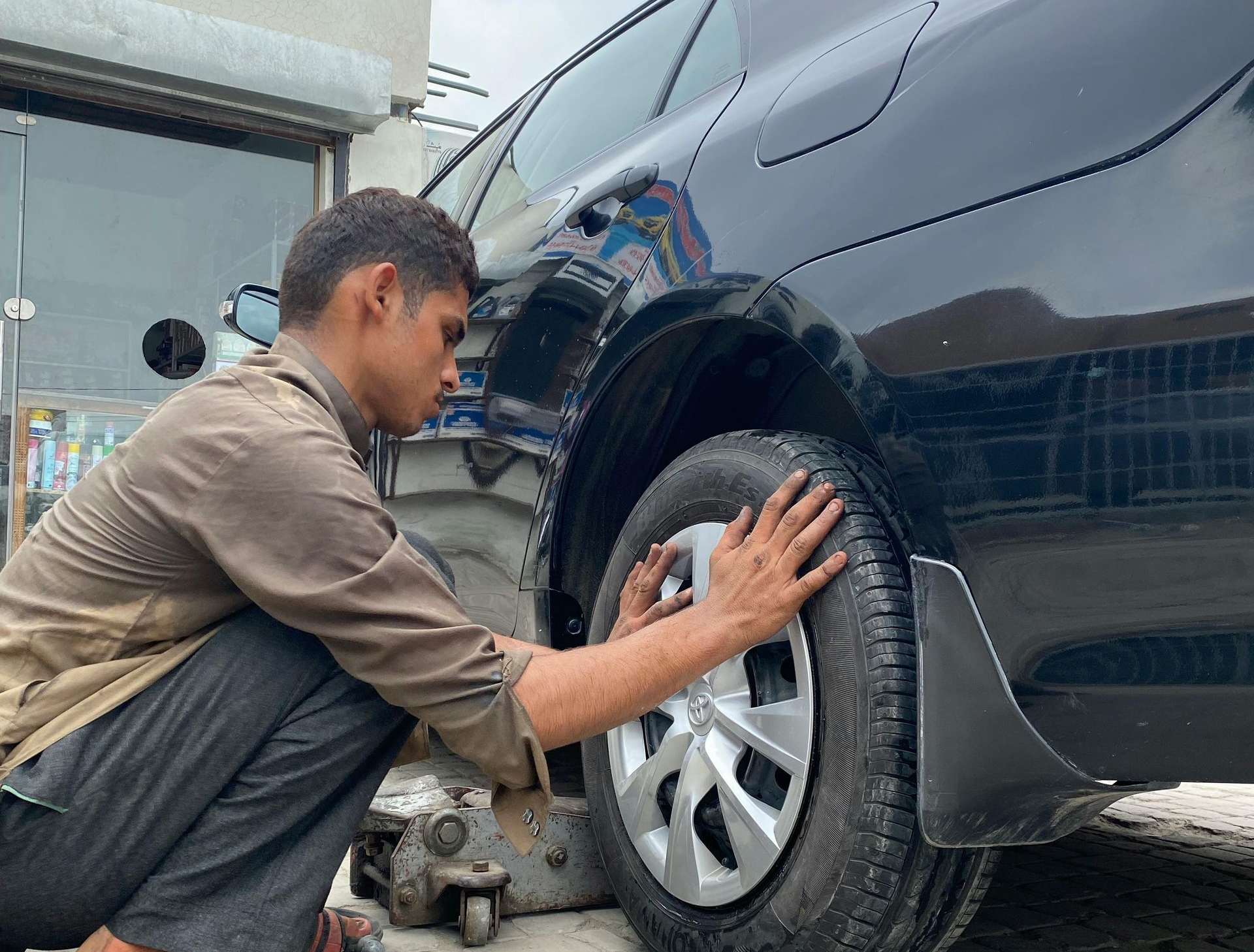 Mechanic inspecting a black SUV’s front wheel in a repair shop