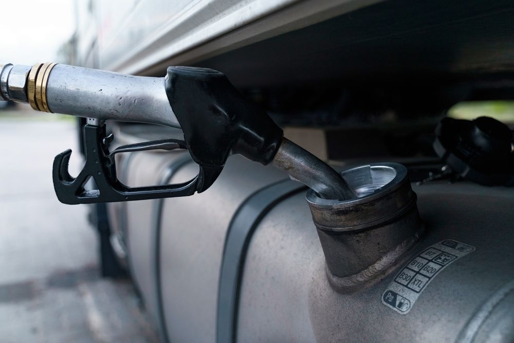 Close-up of a fuel nozzle inserted into a vehicle’s fuel tank opening.