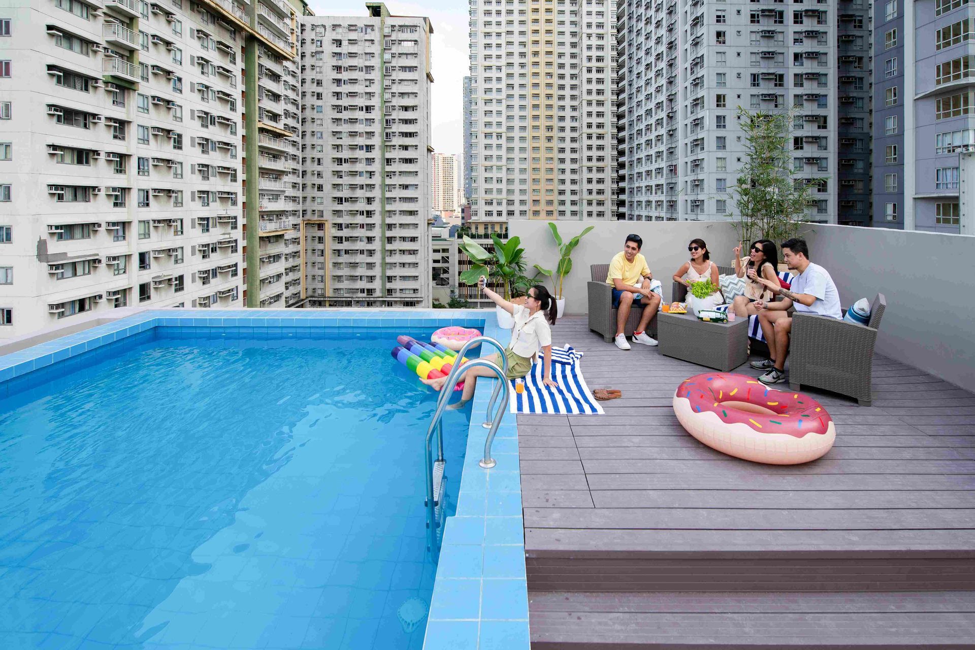 People lounging near rooftop pool, city background.