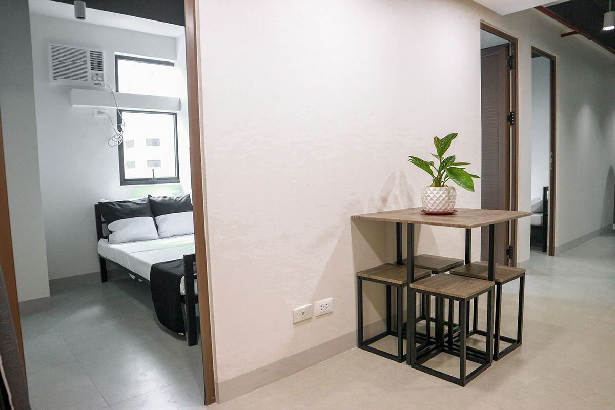 Interior with a bedroom and a table set. Bedroom has a bed. Table has plant.