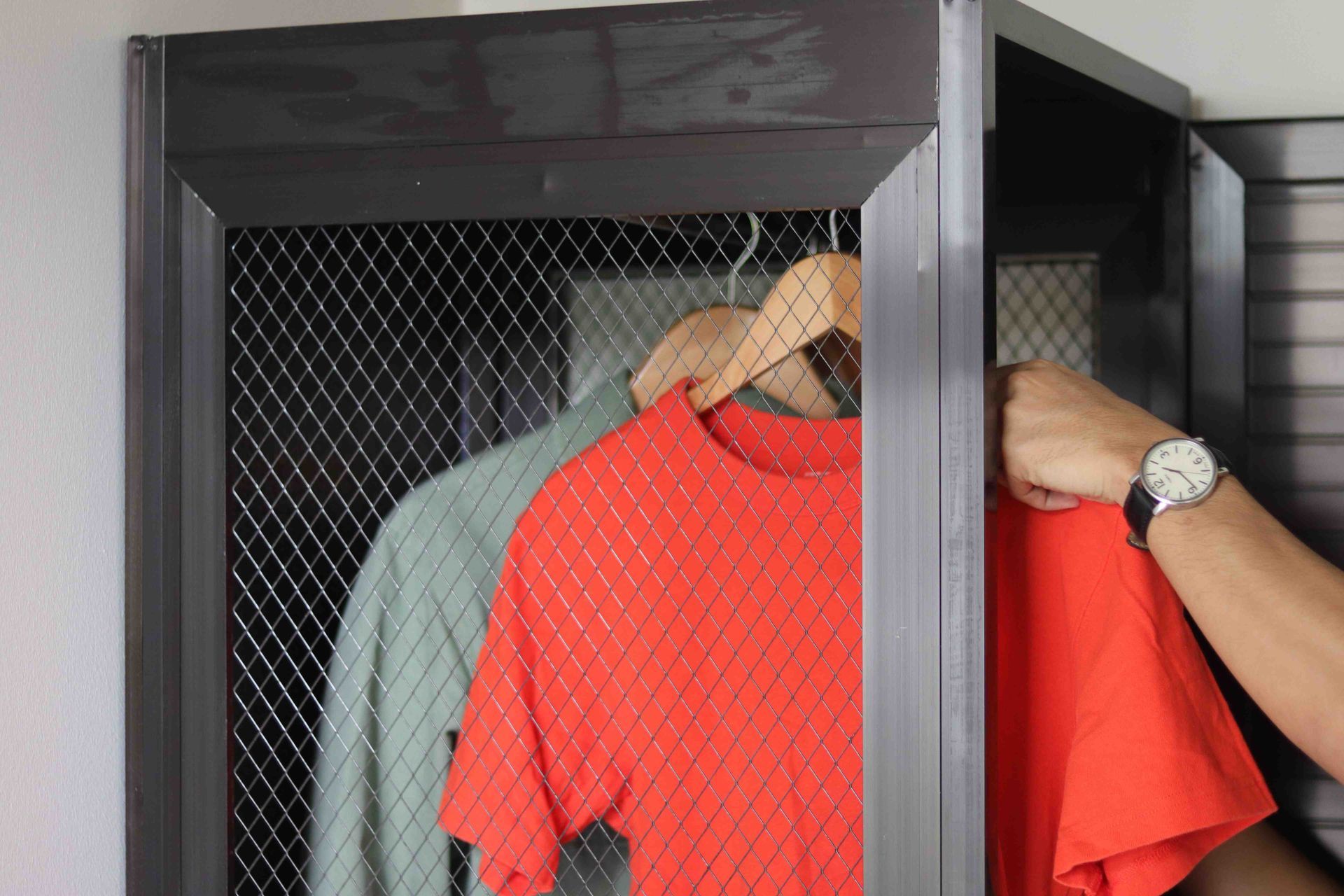 Metal mesh locker with hanging clothes at The Grid Co-Living Makati