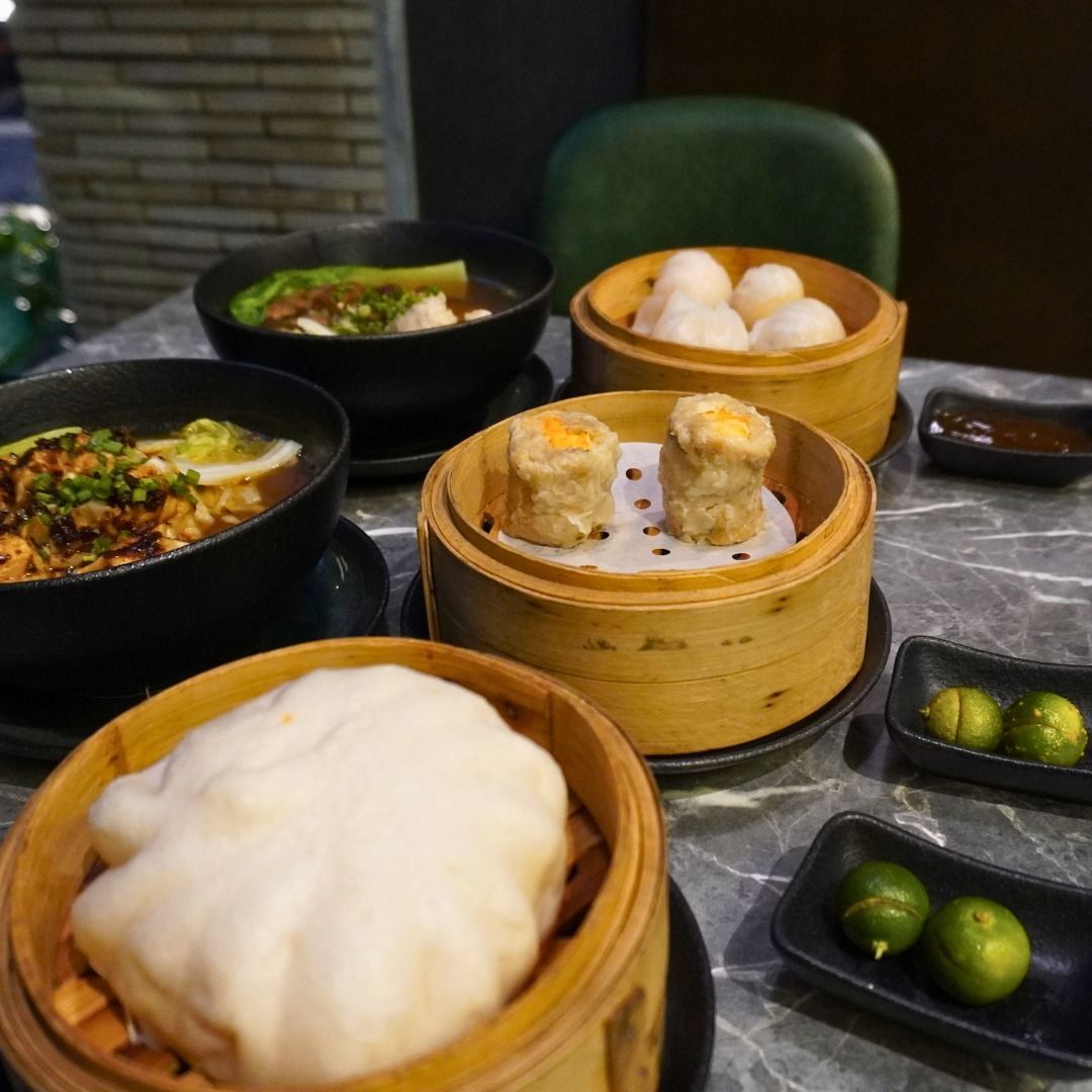 Dim sum spread on a table: dumplings, soup, steamed buns, and dipping sauces.
