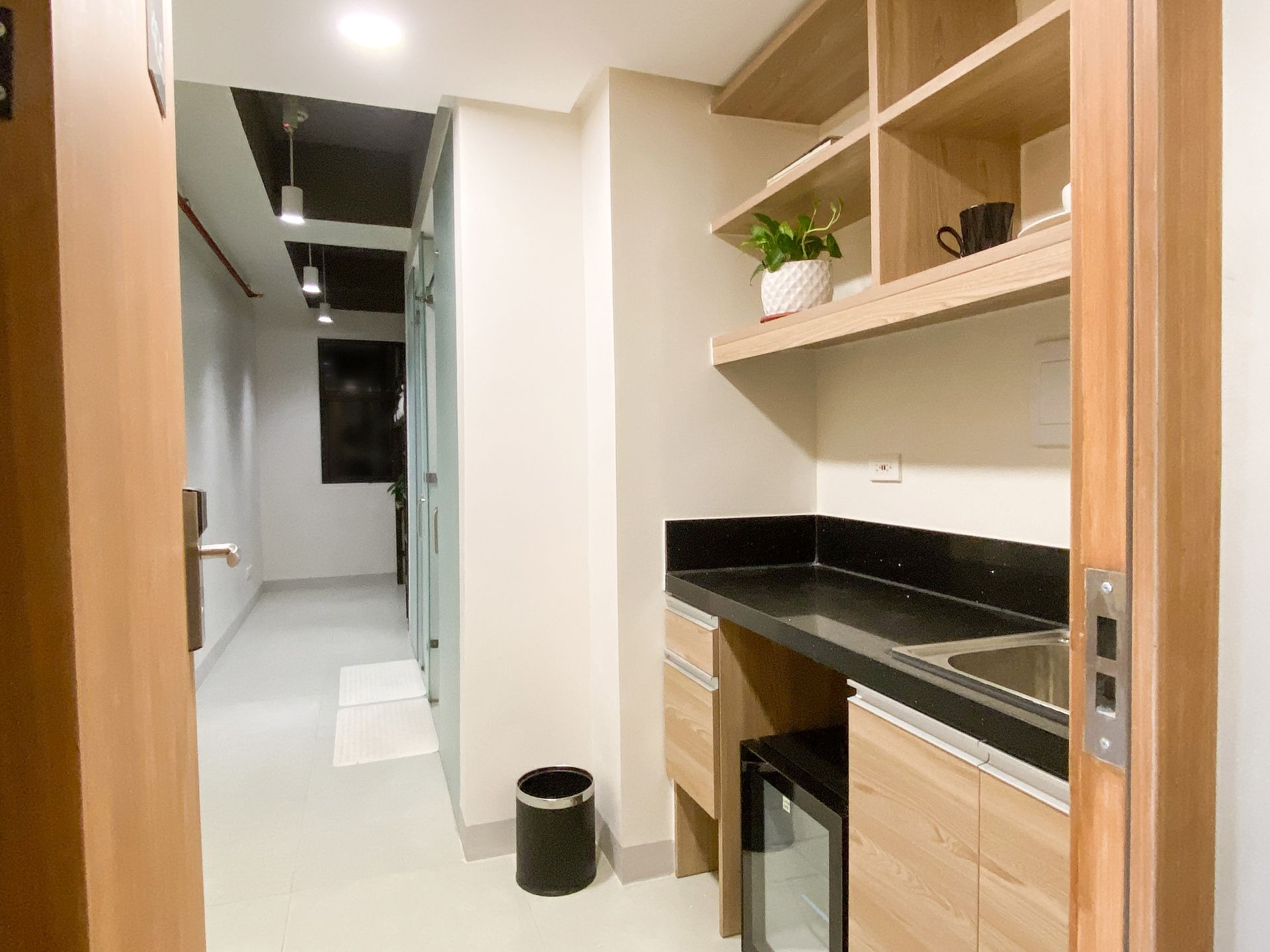 Single Unit at The Grid in Makati with a kitchen: a sink , cabinets , shelves and a trash can.