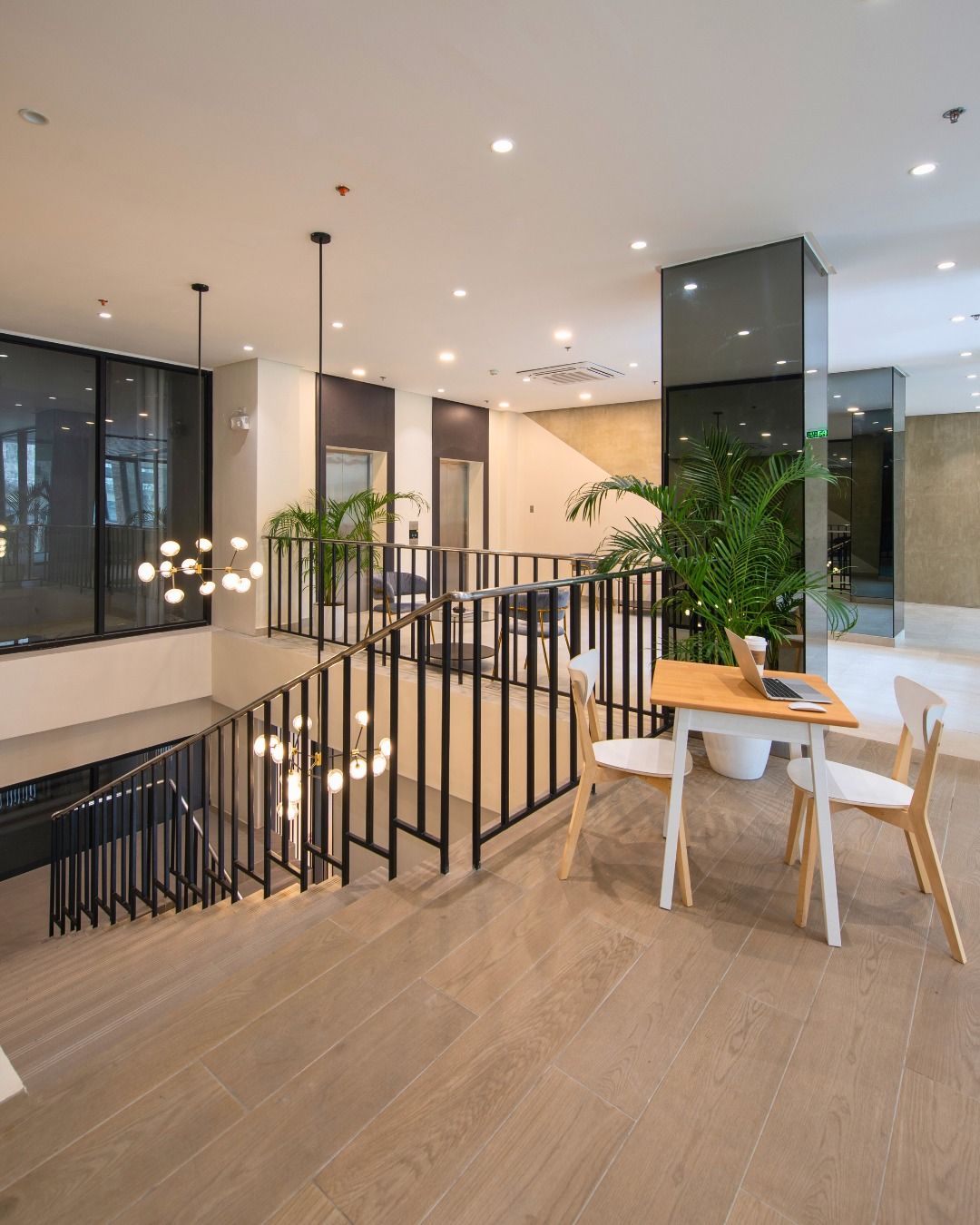 Interior view of a modern building with a staircase, desk, chairs, and potted plants.